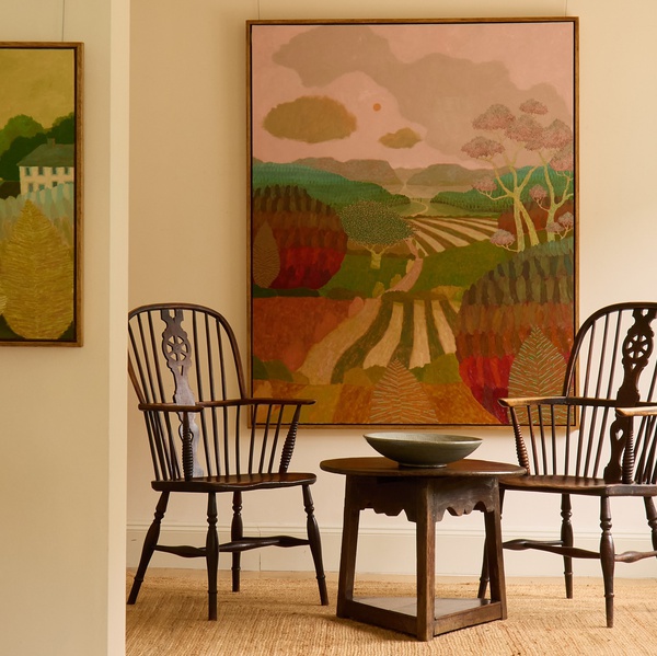 A Richard Ballinger landscape hangs on a wall behind antique furniture and woven rug